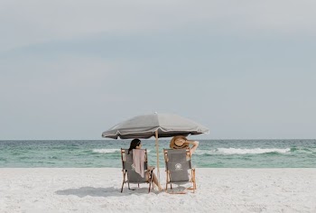 two people under beach umbrella near shoreline