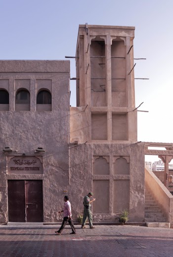 Two People Walking Beside White Building