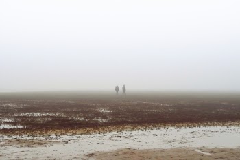 Two People Walking on Fog Covered Field