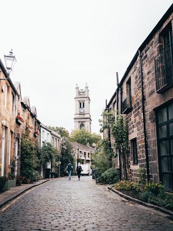 Two People Walking on Pathway Between Buildings
