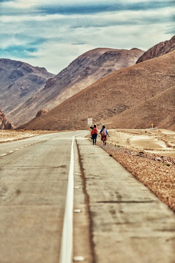 Two People Walking on the Side of the Road
