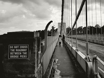 Two People Walking on the Sidewalk of the Bridge
