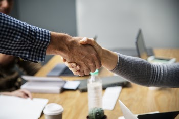 Two Person Doing Handshake Beside Table Inside Room