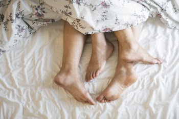Two Person Feet Lying on White Bed