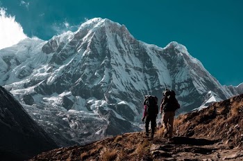 two person hiking near mountain range covered with snow
