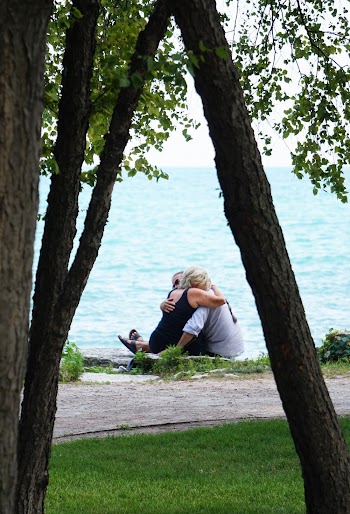 Two Person Hugging While Sitting on Grass