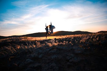 Two Person Jumping on Brown Soil