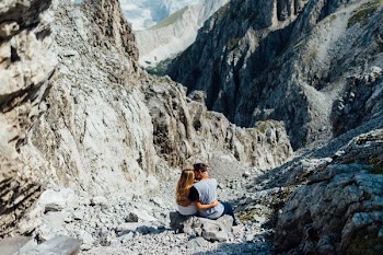 two person kissing each other while sitting on the stone during daytime