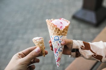 two person's hands holding ice cream cones