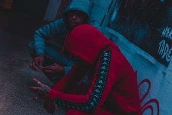 Two Person Sitting Beside Wall