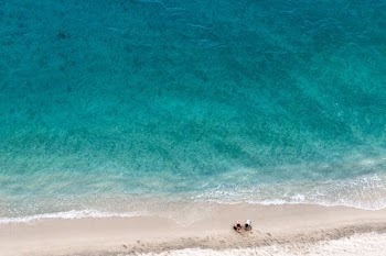 two person sitting on shore near sea at daytime