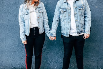 Two Person Standing and Holding Their Hands Beside Blue Wall