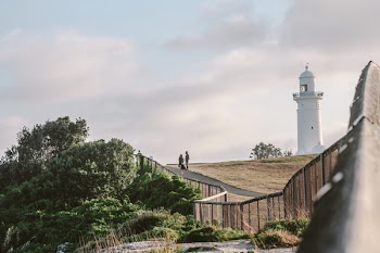 Two Person Standing Near White Lighthouse
