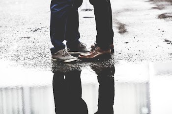 two person standing on road beside body of water