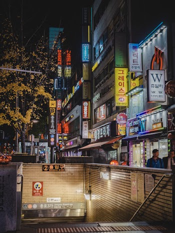 Two Person Walking Beside Building at Nighttime