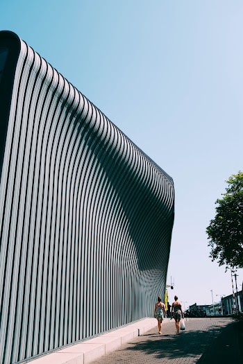 Two Person Walking on Gray Concrete Wall
