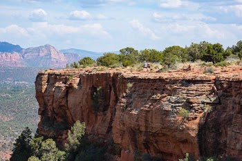 two person walks on brown cliff under clear blue sky during daytime