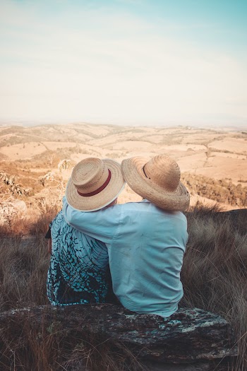 Two Person Wearing Sunhats Sitting on Rock