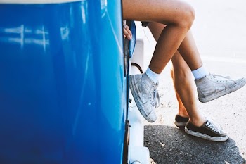 two persons wearing black and white sneakers sitting on vehicle
