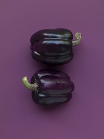 two purple bell peppers on purple surface