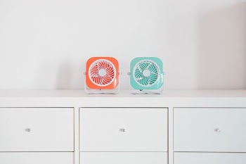 two red and green portable fans on white desk