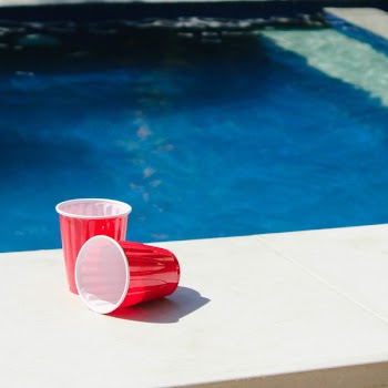Two Red-and-white Disposable Cups on Gray Ceramic Tiles Photo