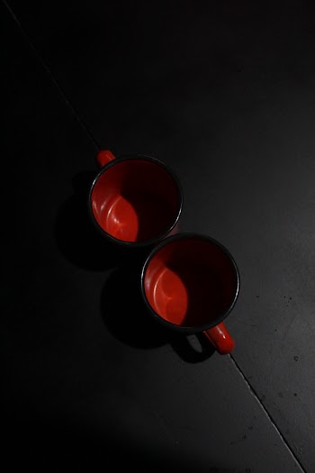 Two Red Ceramic Mugs on Black Surface