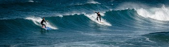 Two Surfers Gliding on Body of Water