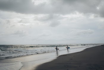 Two Surfers Standing On Beach