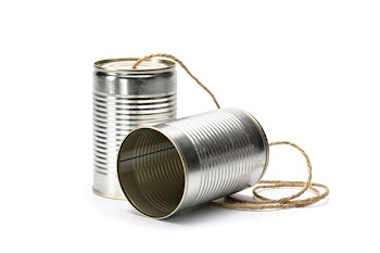Two tin cans connected by string on white background, suggesting...