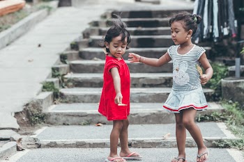 Two Toddler Wearing Red and Gray Dresses