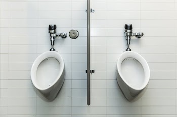 Two Urinals On White Tile Wall