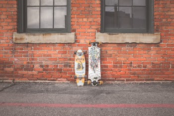Two White and Brown Longboard Leaning on Brown Bricks Wall