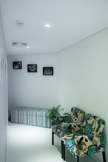 Two White and Green Floral Padded Sofa Chairs Next to Wall in Room