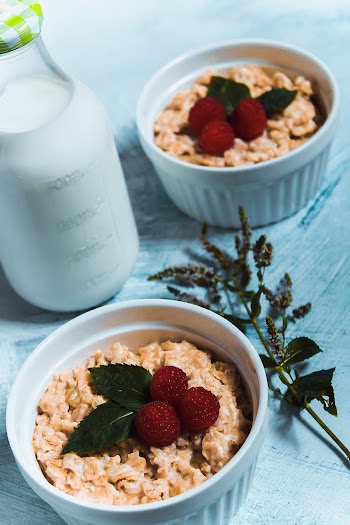 Two White Ceramic Bowls With Cereal Beside Milk Bottle