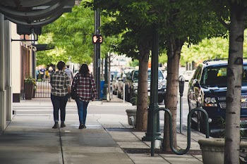 Two Woman in Plaid Sport Shirt Walking on Concrete Pathway Near Street