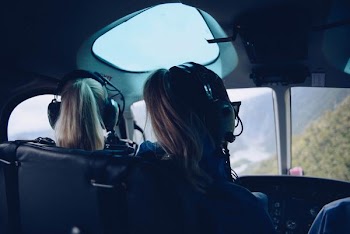 two woman sitting inside helicopter using headphones