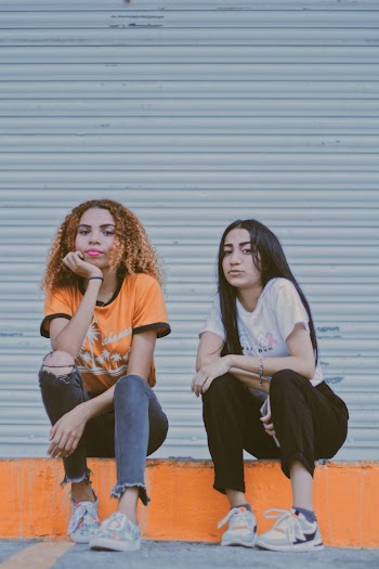 Two Woman Sitting on Orange Concrete Pathway