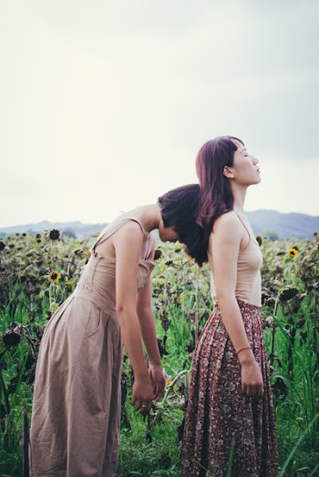 Two Woman Standing Near Sunflower Field at Cloudy Sky