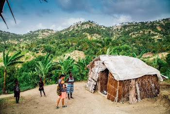 Two Women and Children Standing in Front of Hut