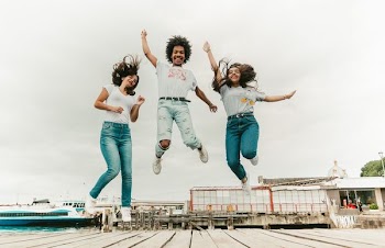 two women and one man jumping at daytime