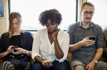 Two Women and One Man Sitting in Front of Window Using Smartphones