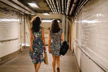 Two Women Carrying Bags While Walking in Tunnel