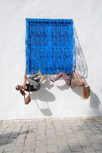 Two Women Clinging on Window Rails