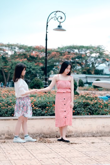 Two Women Holding Hands Under Green Metal Post Lamp