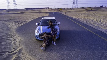 Two Women In Front Of Mini Cooper Parked In The Middle Of The Road