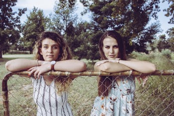 Two Women Leaning on Chain Link Fence