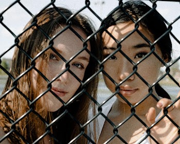 Two Women Leaning on Chain-link Fence