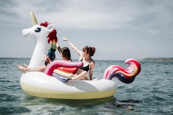 Two Women On Unicorn Floater On Sea