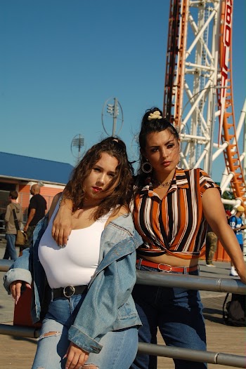 Two Women Posing While Leaning on Metal Railing